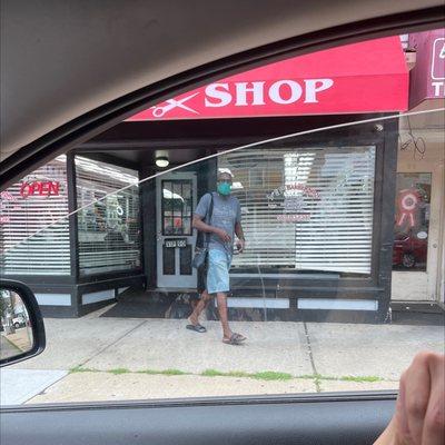 Was shaping up this bald man's head...while the other five barbers talked and was laughing.