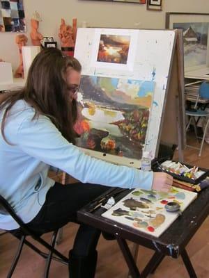 A high school student is finishing  her painting