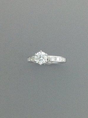 This gorgeous round center diamond is highlighted by square cut diamonds channel set in the shank