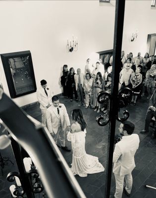 Lovely view from top of stairs while wedding couple exchange vows as guitarist, Alex Guillen watches from above, ready to play exit music.