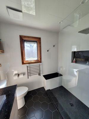 Custom shower with a tile and granite bench and a heated towel warmer.