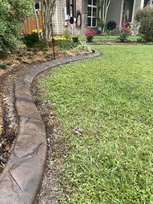 Continuous concrete bed border in a fractured quartz look - Walnut Brown with Charcoal accents.