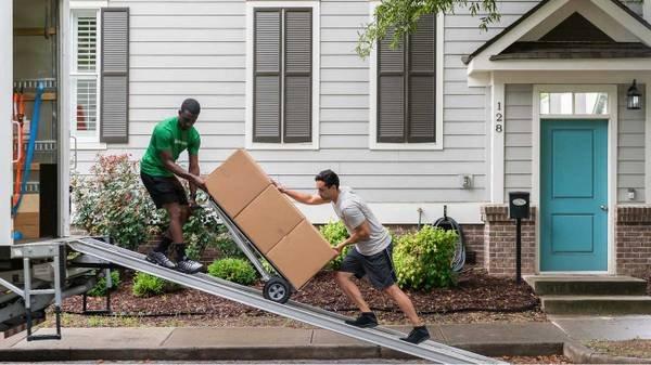 2 movers moving items up a ramp.