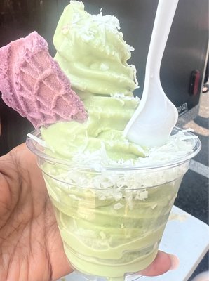 Matcha soft serve with shredded coconut topping and ube shortbread cookie.