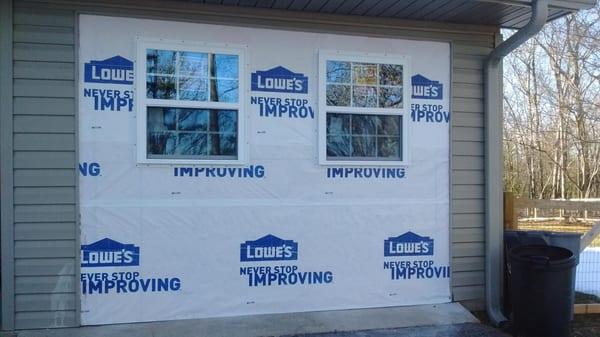 Where there once was a garage door now stands a wall with two windows.