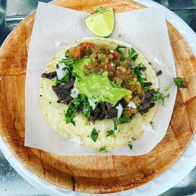 Asada taco, served with chopped onion and cilantro, avocado and a Tijuana style salsa.