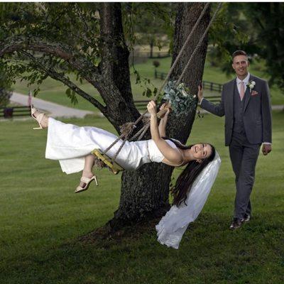 Beautiful couple with bride swinging on swing at Hilltop Farm Venue.