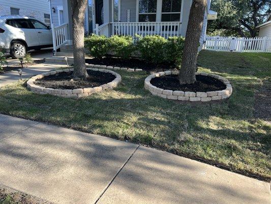 Full Front side Sod installation with Stone flower beds filled with black multch for the trees.