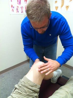 Dr. Williams kinesiotaping a patient's left knee