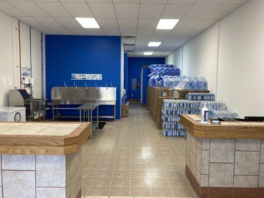 Empty water bottle refill sink and case's of different bottled waters.