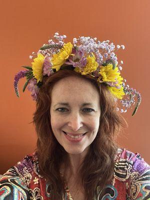 A woman wearing a crown of yellow, purple and white flowers.