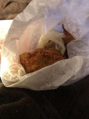 An oily piece of napkin wrapped around chicken inside the bag