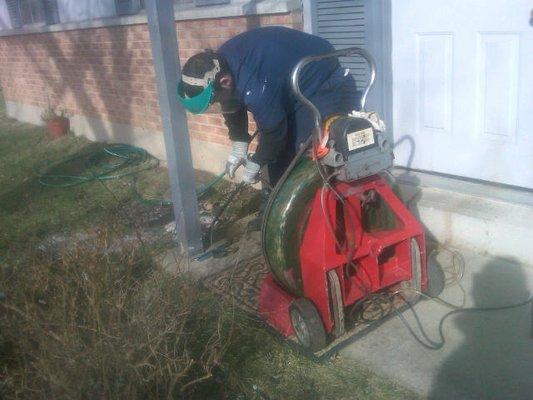 Brandon 3rd generation family member,  on job cleaning roots out of drain for customer.