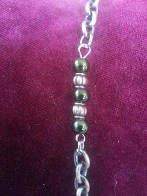 Green beads and copper colored spacers embedded in the link chain of Starburst necklace