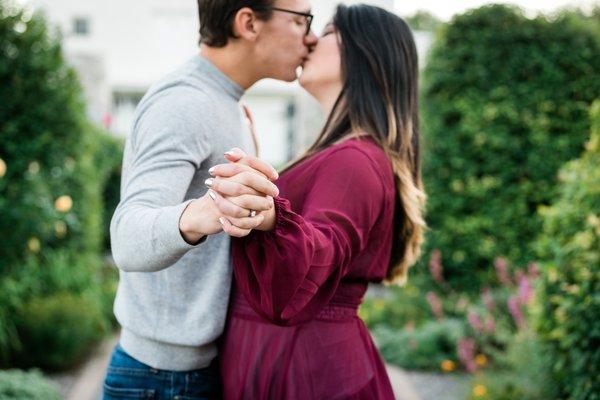 A couple kisses showing off the engagement ring