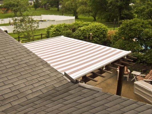 This motorized, retractable pergola cover in Cotuit provides both shade and rain protection.