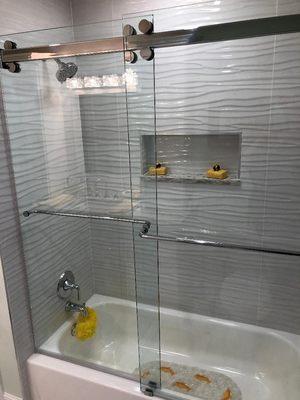 By-pass barn style shower doors featuring full Titan wave shower walls designed by Apollo Kitchen & Bath.