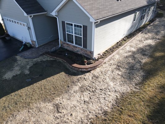 Sidewalk with garden wall and curb stone on the side ot the house