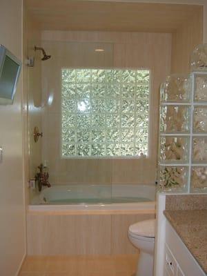 Complete bathroom remodel with glass block window and division wall, jetted tub, lots of tile, and a TV.