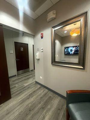 A hallway with a small waiting area next to bathroom