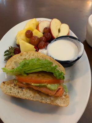 Half Salmon Sandwich with fruit as the side.