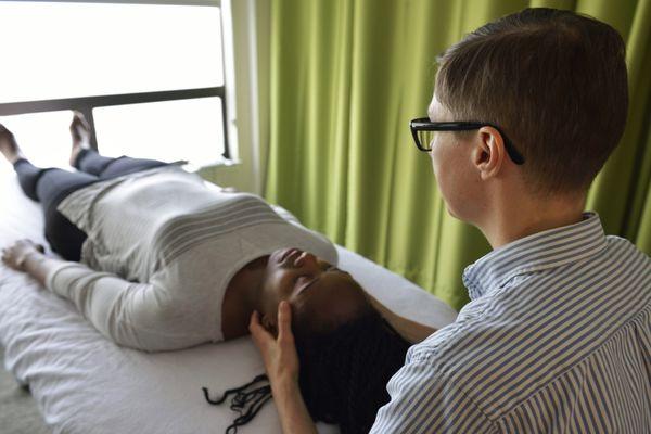 Performing craniosacral therapy as patient relaxes