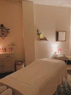 Dimly lit massage studio. Essential oils and candles on shelves. Handmade organic aromatherapy massage oils.