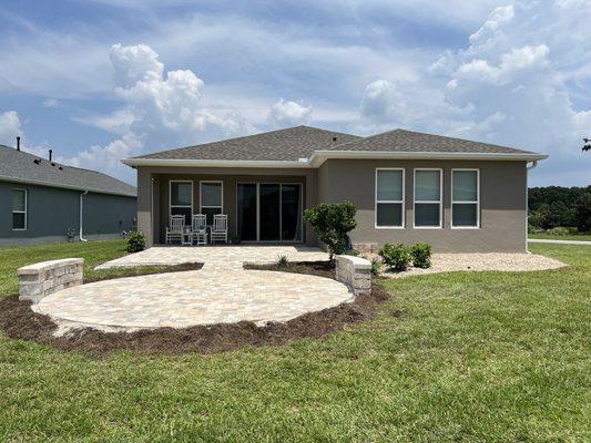 Rear yard paver brick patio and ornamental River Rock.