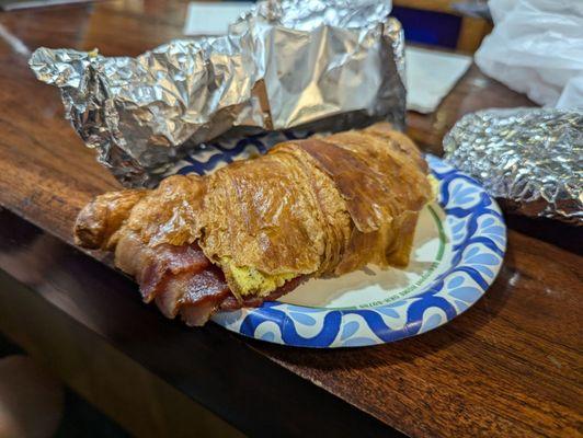 Breakfast croissant has thick bacon, egg patty, and cheese