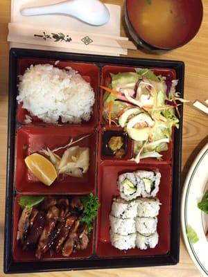 Box of bento with chicken teriyaki and California rolls. Also a side of tofu miso soup.