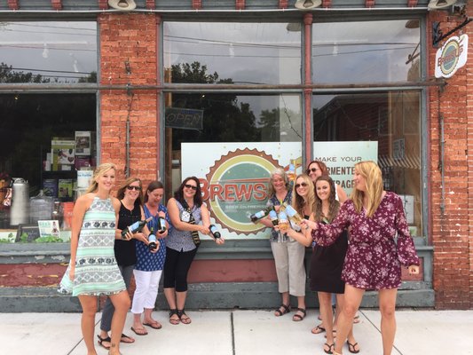 Ladies posing with the bottles of wine they made