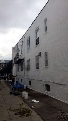 Waterproofing the side of a house using thorocoat coating on a rope scaffold.