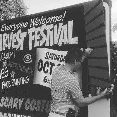 Pastor Kevyn putting up annual Harvest fest signage