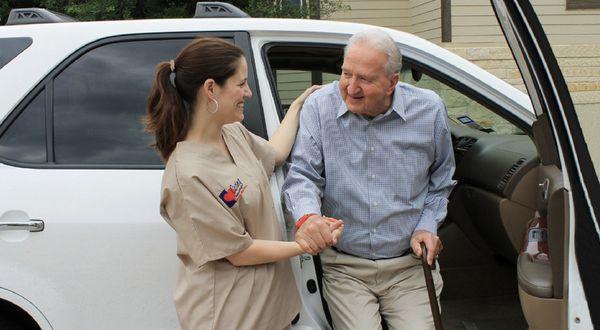 Caregiver assisting Senior out of the vehicle.