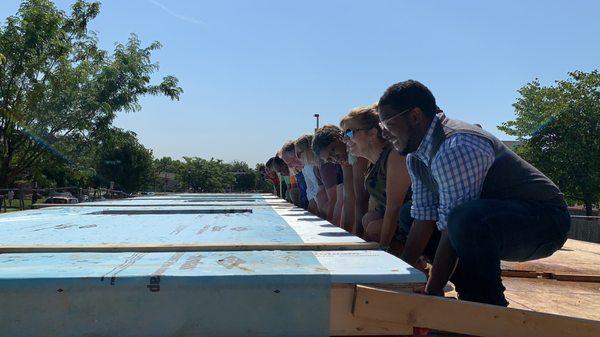 Volunteers raise a wall at a build site.