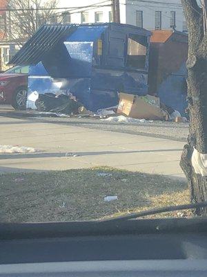 Trash can (facing main thoroughfare) overflowing with trash, per usual