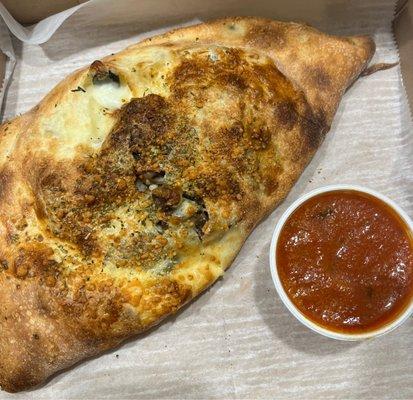 Calzone with veggies. Cooked well and good amount of filling. Served with small cup of sauce.