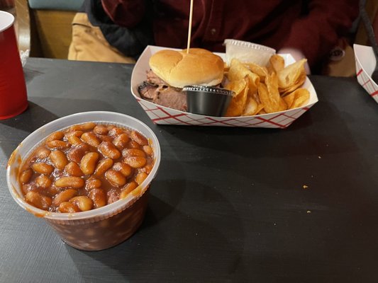 Brisket sandwich and chips with beans on the side