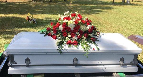 Casket spray with red roses.