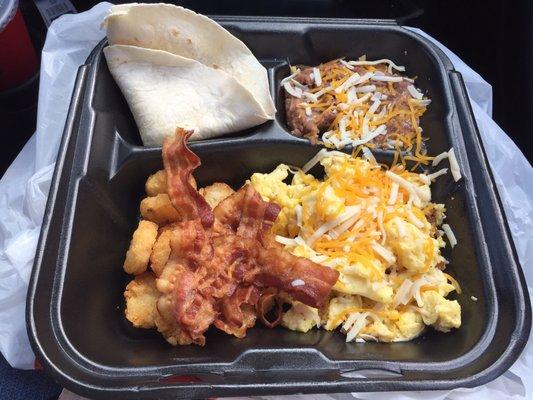 Breakfast platter with scrambled eggs and cheese, refried beans, bacon, hash brown bites and flour tortillas.