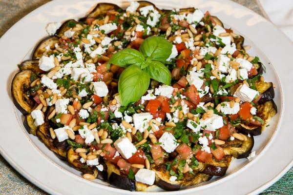 Roasted Eggplant topped with fresh tomato, basil, feta cheese, garlic and roasted pine-nuts