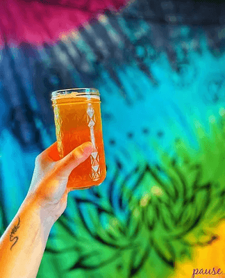 Kratom tea in front of a colorful tapestry at Pause Kava Bar