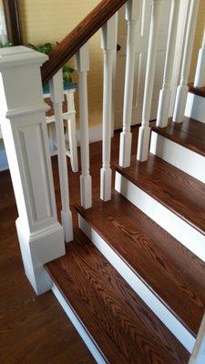 Stained return treads, skirt boards, Raised panel oversized box newel and wood balusters.