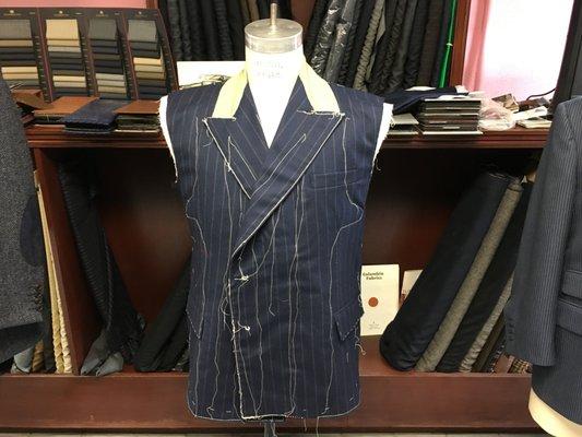 A double-breasted blue with chalk stripes suit made by John Di Pietro basted together for fitting.