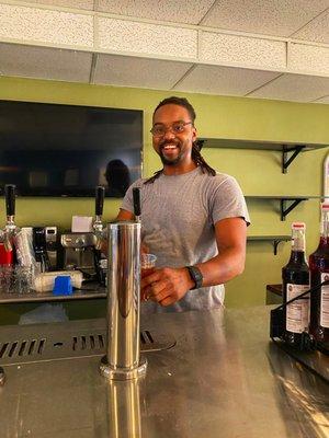 Employee standing behind the bar pouring kratom on tap