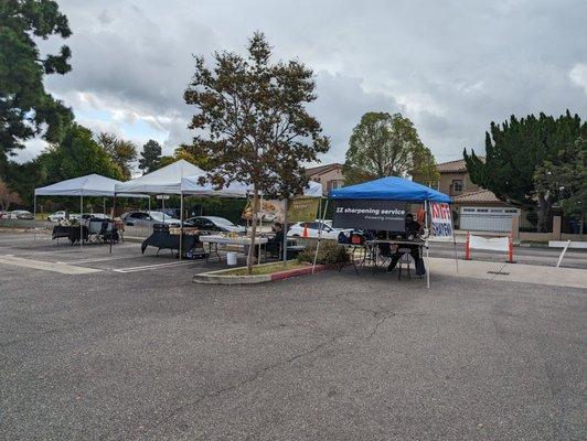 blue tent over the knife sharpener stand in action, next to white tents over other prepared food vendors