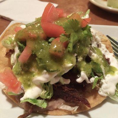 Salsa Verde on top of a Carnitas Tostada