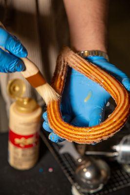 Painting a Churro with white chocolate sauce