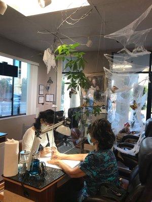 Manicurist working on a client. All safety guidelines have been implemented. The salon was also decorated really cute for Halloween.