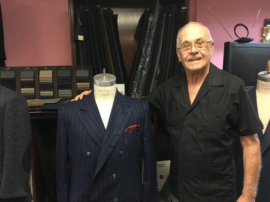 John Di Pietro standing with adouble-breasted blue with chalk stripes suit that he made.